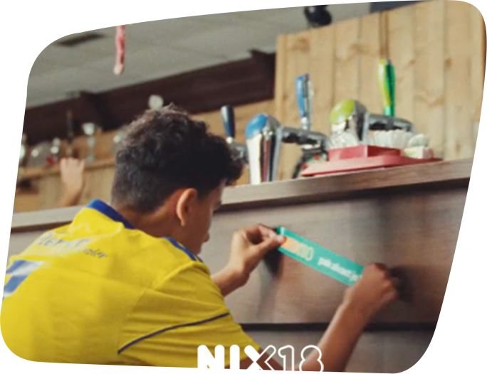 Jongen plakt nix18 sticker op bar sportkantine